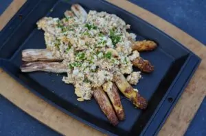 Spiegeleier-Salat mit gebratenem grünem Spargel auf schwarzem Servierbrett, garniert mit gehackter Petersilie