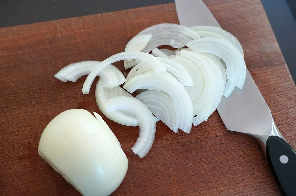 Die Zwiebeln werden in halbe Ringe geschnitten
