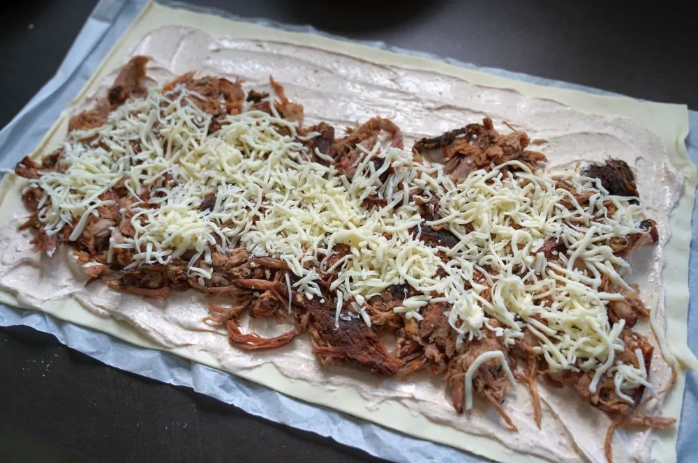 Pulled Pork und Käse werden auf dem Blätterteig verteilt