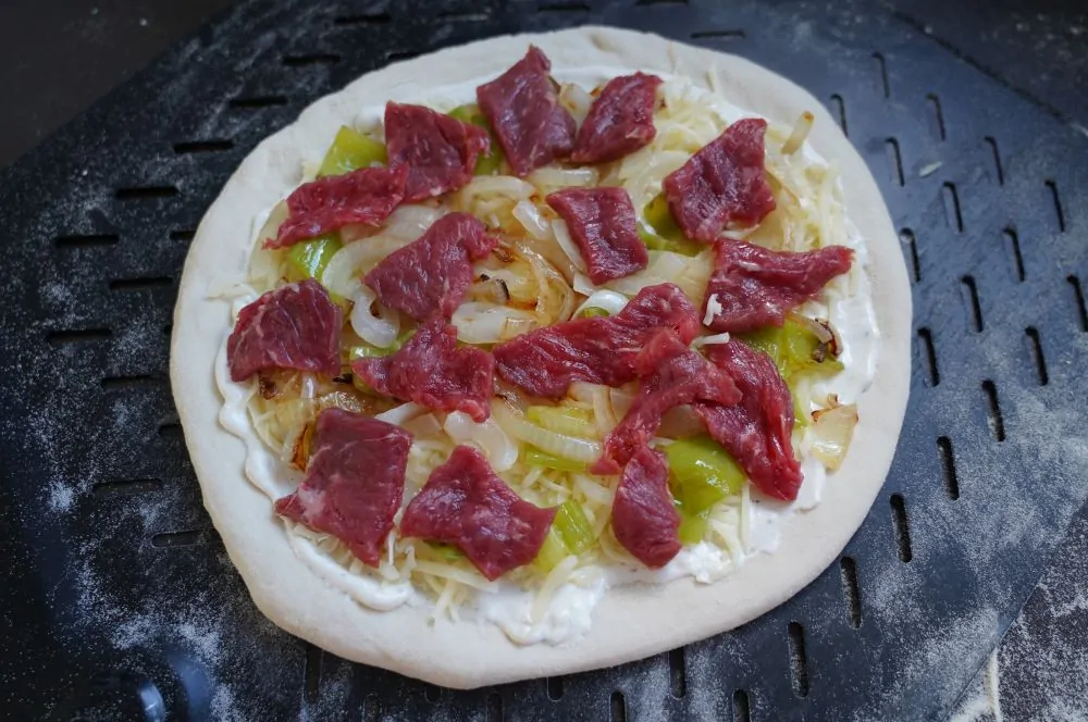 Die Philly Cheesesteak Pizza wird belegt